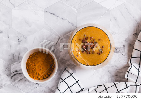 Close up of smoothie made from coconut milk, banana, turmeric and flax seeds in a glass top view Close up of smoothie made from coconut milk, banana, turmeric and flax seeds in a glass top view 137770000