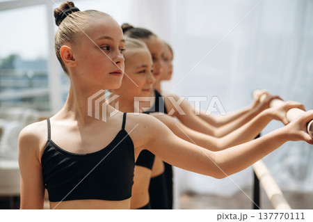 Standing together. Girls practicing ballet indoors in the class Standing together. Girls practicing ballet indoors in the class 137770111