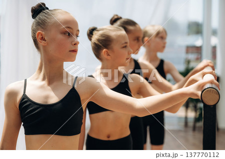 Standing together. Girls practicing ballet indoors in the class Standing together. Girls practicing ballet indoors in the class 137770112