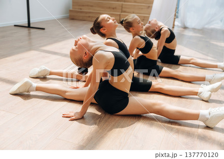 On the floor. Girls practicing ballet indoors in the class 137770120