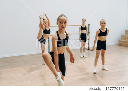 Four people. Girls practicing ballet indoors in the class Four people. Girls practicing ballet indoors in the class 137770125