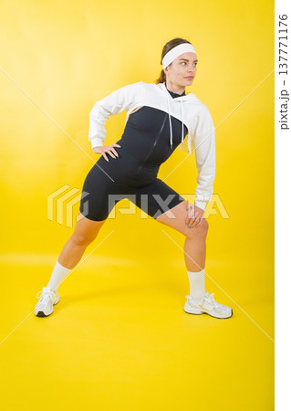 Woman stretching in sporty jumpsuit and cropped hoodie Woman stretching in sporty jumpsuit and cropped hoodie 137771176