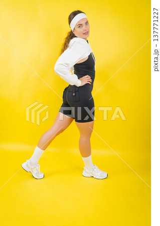 Young woman posing in athletic wear on yellow background Young woman posing in athletic wear on yellow background 137771227