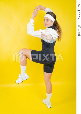Young woman performing fitness exercise against yellow background Young woman performing fitness exercise against yellow background 137771229