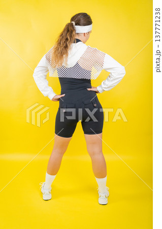 Woman posing in retro fitness wear with hands on hips 137771238