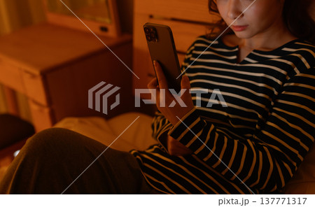 暗い部屋でスマホを操作する女性 137771317