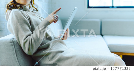 タブレットを指差す女性の手元と膝 タブレットを指差す女性の手元と膝 137771325