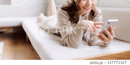 ソファでスマホを操作する女性 137771327