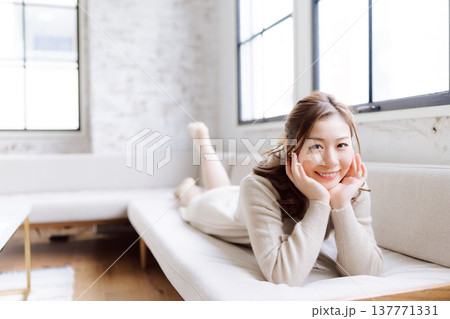 ソファで横になり微笑む女性 137771331