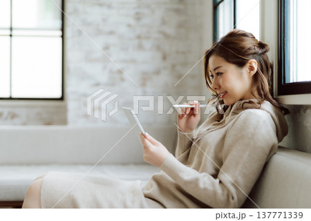 ソファでタブレットに向かう女性の横顔 ソファでタブレットに向かう女性の横顔 137771339