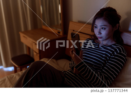 ベッドでスマホを見る女性 ベッドでスマホを見る女性 137771344
