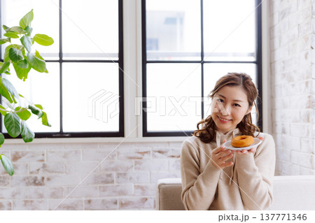 窓辺でドーナツを持つ明るい女性 窓辺でドーナツを持つ明るい女性 137771346