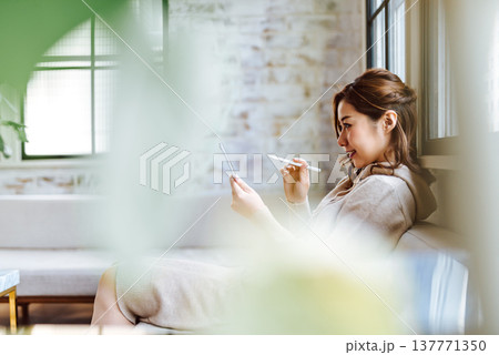 観葉植物越しにタブレットを使う女性 観葉植物越しにタブレットを使う女性 137771350