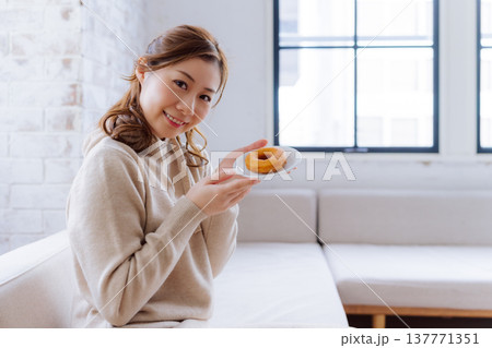 ドーナツを手に持ち微笑む女性 137771351