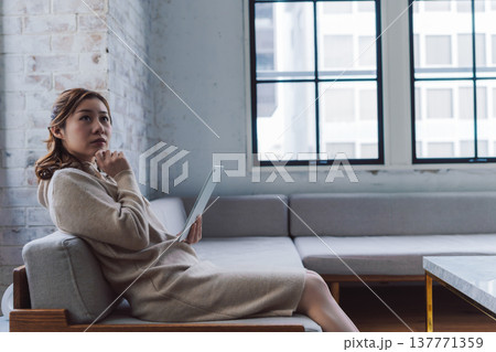 タブレットを持ち考え込む女性 137771359
