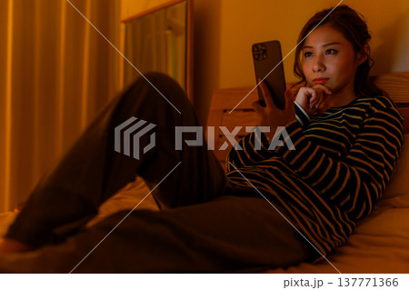 ベッドでスマホを見る女性 137771366