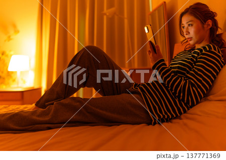 ベッドでスマホを見つめる女性 ベッドでスマホを見つめる女性 137771369