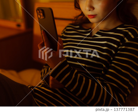 ベッドでスマホを見つめる女性 137771387