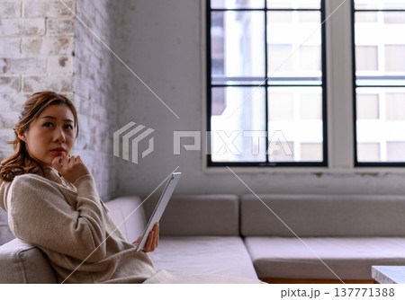 タブレットを見つめ考える女性 137771388
