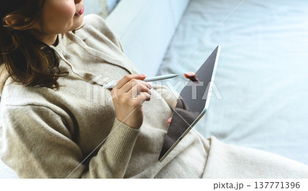 タブレットとペンを持つ女性の手元 137771396