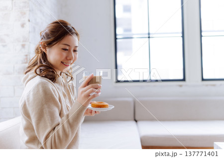自宅でカフェラテとドーナツを楽しむ女性 自宅でカフェラテとドーナツを楽しむ女性 137771401