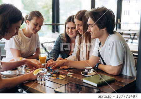 Having fun by playing the game by table. Group of young friends are in the cafe restaurant Having fun by playing the game by table. Group of young friends are in the cafe restaurant 137771497