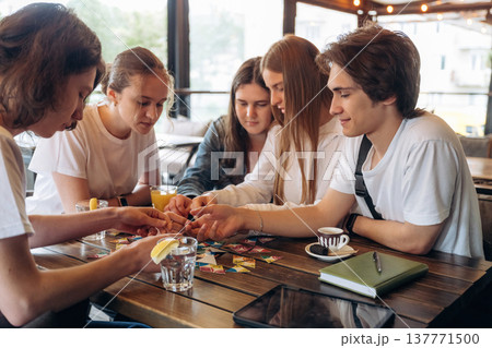 Wellness, playing card game. Group of young friends are in the cafe restaurant Wellness, playing card game. Group of young friends are in the cafe restaurant 137771500