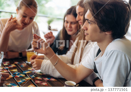 Wellness, playing card game. Group of young friends are in the cafe restaurant 137771501