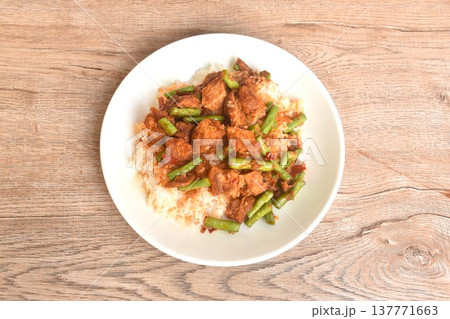 spicy stir fried slice yard long bean with crispy pork and lemon grass in curry sauce on rice in plate spicy stir fried slice yard long bean with crispy pork and lemon grass in curry sauce on rice in plate 137771663