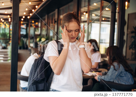 Girl is having a headache. Group of young friends are in the cafe restaurant Girl is having a headache. Group of young friends are in the cafe restaurant 137771770
