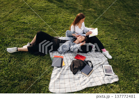 Two girls students are on the grass, outdoors 137772481