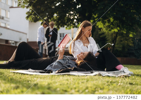 On the ground, lying down. Group of students are near university together 137772482