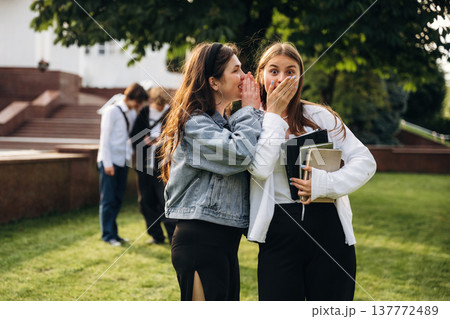 Telling a secret, gossip. Group of students are near university together 137772489