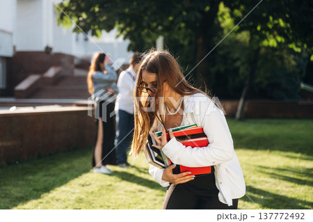 Bunch of notepads in hands of a girl. Group of students are near university together 137772492
