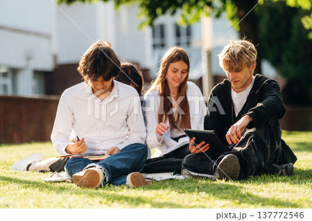 Under sunlight, sitting. Group of students are near university together Under sunlight, sitting. Group of students are near university together 137772546