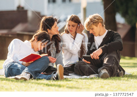 Under sunlight, sitting. Group of students are near university together Under sunlight, sitting. Group of students are near university together 137772547