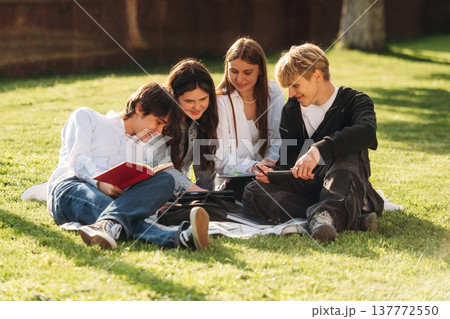Reading together. Friends students are outdoors Reading together. Friends students are outdoors 137772550