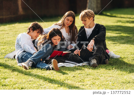 Reading together. Friends students are outdoors Reading together. Friends students are outdoors 137772552