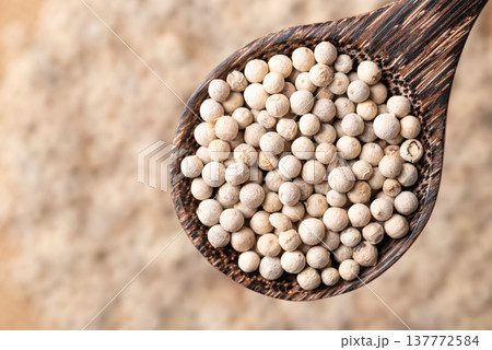 Close up of white peppercorns in a wooden spoon, essential spices and seasoning for cooking Close up of white peppercorns in a wooden spoon, essential spices and seasoning for cooking 137772584
