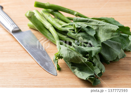 Fresh Chinese kale or Chinese broccoli (Gai Lan) with kitchen knife on wooden cutting board Fresh Chinese kale or Chinese broccoli (Gai Lan) with kitchen knife on wooden cutting board 137772593