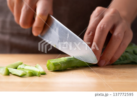 Hand using a knife to cut fresh Chinese kale or Chinese broccoli (Gai Lan) on wooden board Hand using a knife to cut fresh Chinese kale or Chinese broccoli (Gai Lan) on wooden board 137772595