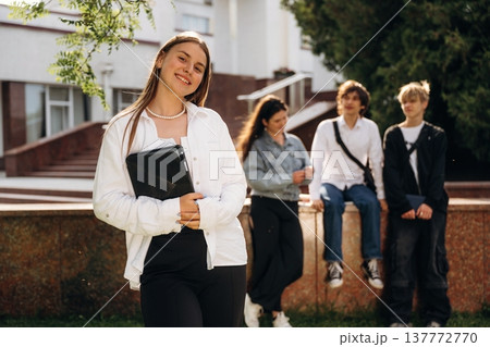 Girl is standing in front of her friends. Group of students are near university together 137772770