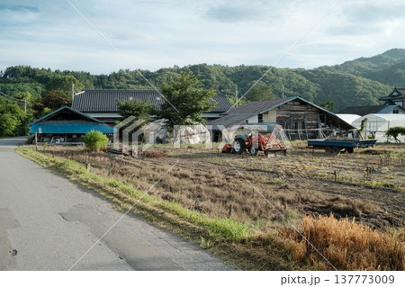 農作業場とトラクターが並ぶ山里の夏の風景 農作業場とトラクターが並ぶ山里の夏の風景 137773009