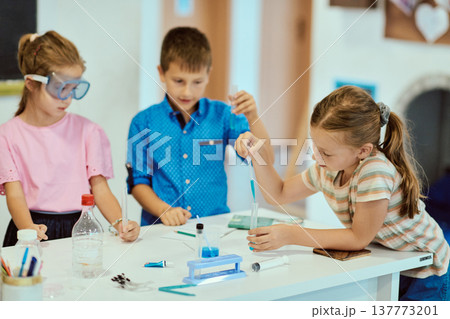 Children doing a hands-on science experiment in a bright classroom learning together Children doing a hands-on science experiment in a bright classroom learning together 137773201