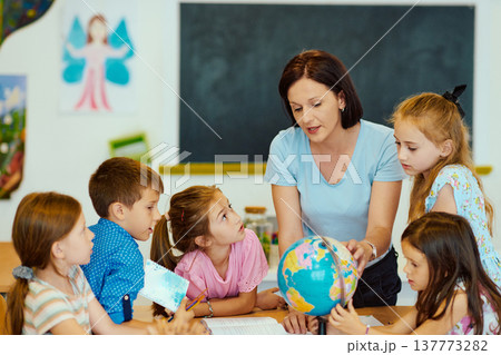 Teacher shows globe to a group of elementary students in a classroom geography lesson 137773282