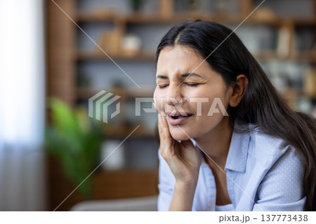 Woman grimacing from a sharp toothache, clutching her cheek and jaw in pain, conveying urgent dental discomfort, worry, and need for immediate dental care or treatment 137773438