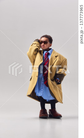 Little boy wearing oversized coat tie and sunglasses posing confidently in studio. Little boy wearing oversized coat tie and sunglasses posing confidently in studio. 137773965