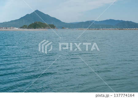 若狭の海越しに望む山並みと静かな海岸風景 137774164