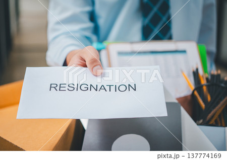 Hand holding a resignation envelope After resigning from work to find a new job , was fired by the company or when the employment contract expires, resulting in being unemployed Hand holding a resignation envelope After resigning from work to find a new job , was fired by the company or when the employment contract expires, resulting in being unemployed 137774169