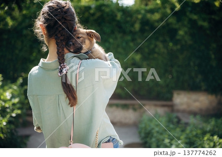View from behind. Woman is standing and holding cute dog 137774262